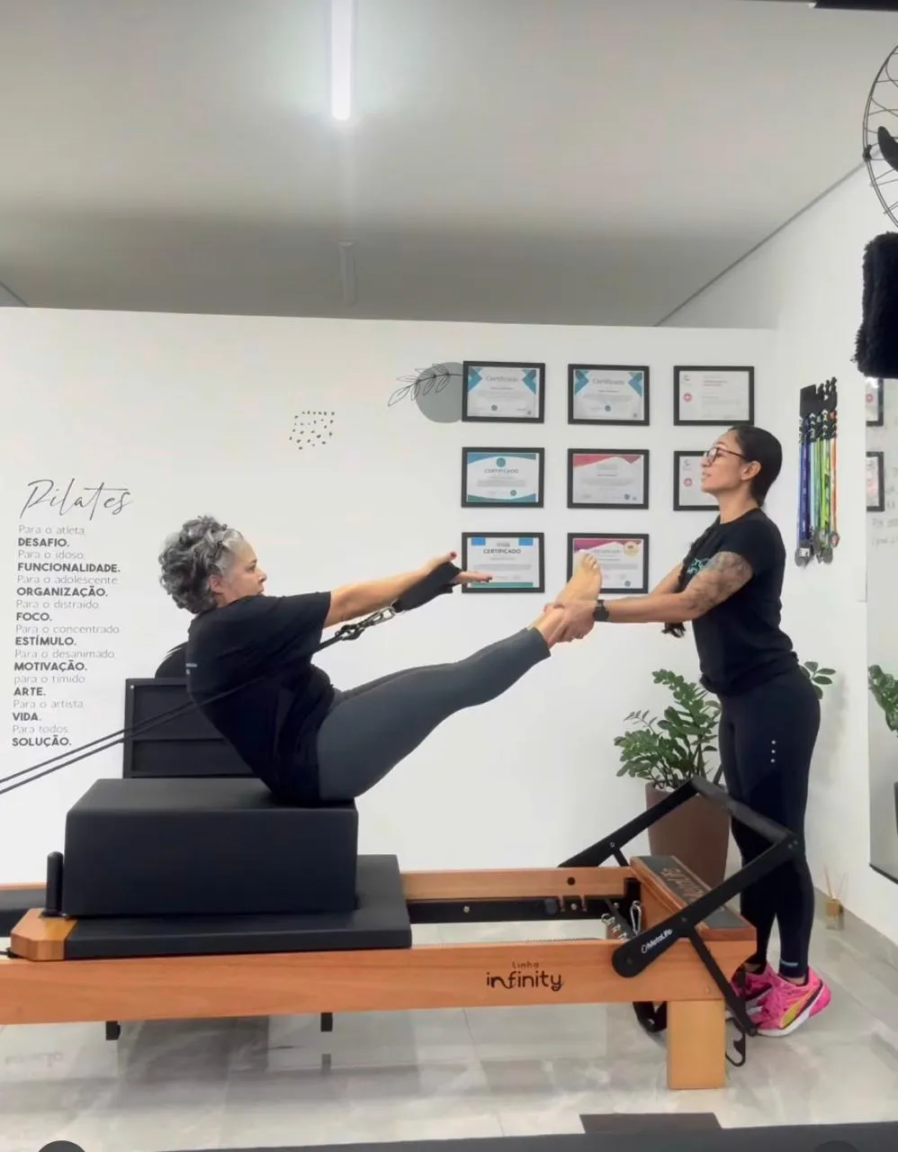 Denise Vendeirinho segura os pés de uma aluna durante um exercício no reformer, no estúdio em Santo André