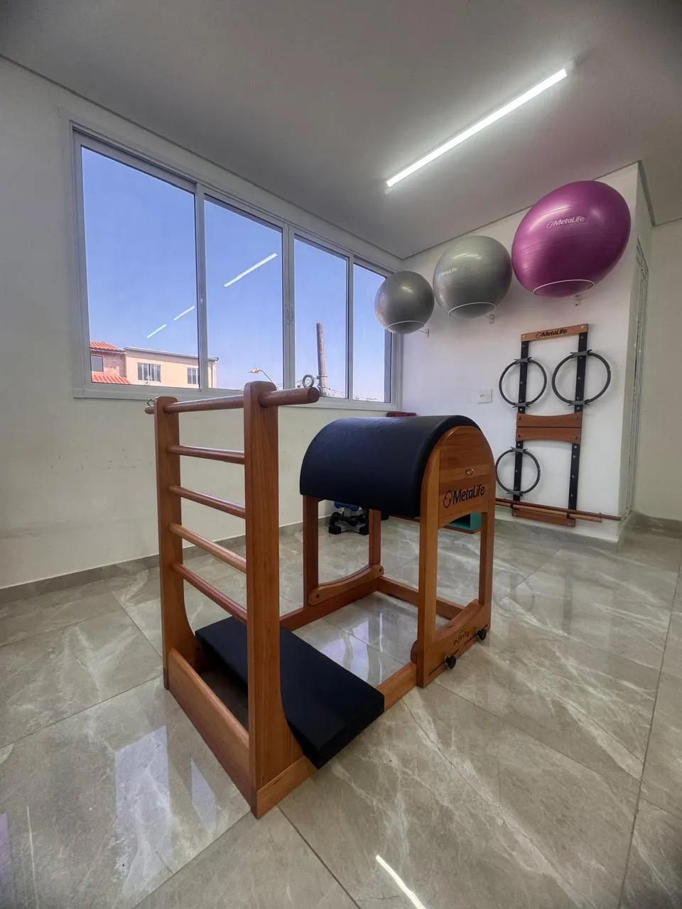 Ladder barrel de madeira perto da janela, com bolas de Pilates na parede